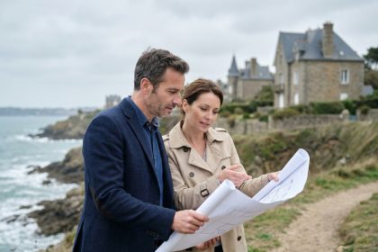 Couple de professionnels étudiant des plans architecturaux sur les falaises de Dinard avec des villas bretonnes en arrière-plan